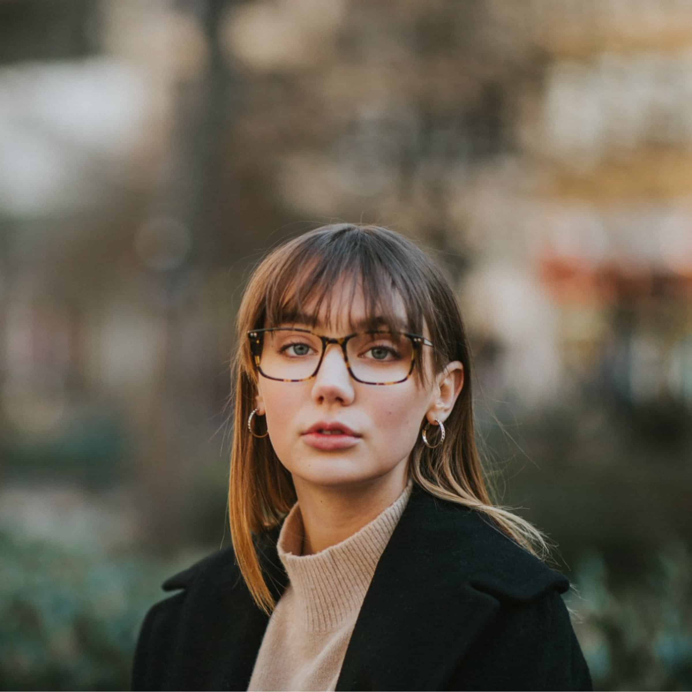 Woman with straight hair and hoop earrings wearing tortoiseshell glasses