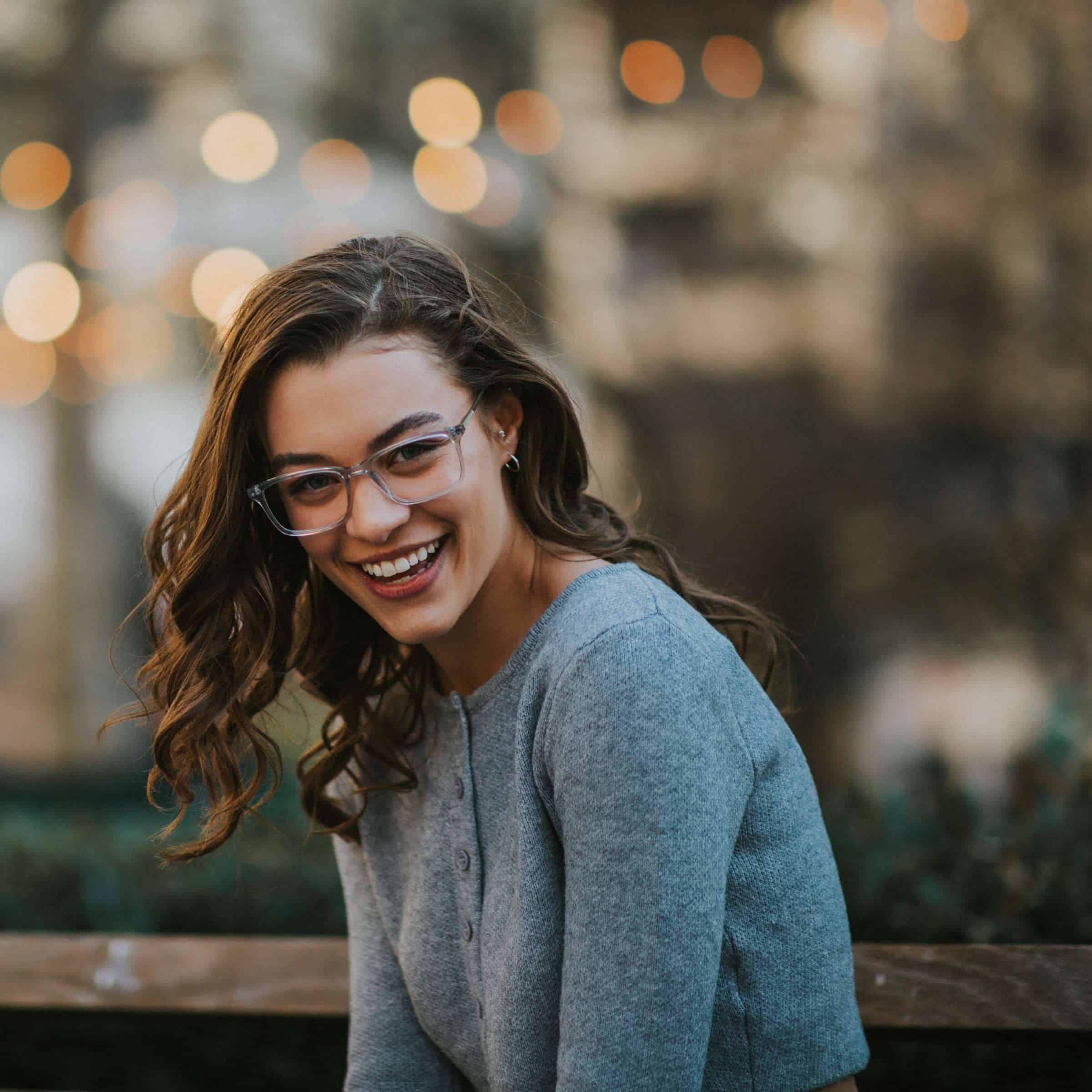 Smiling woman with curly hair wearing translucent glasses.