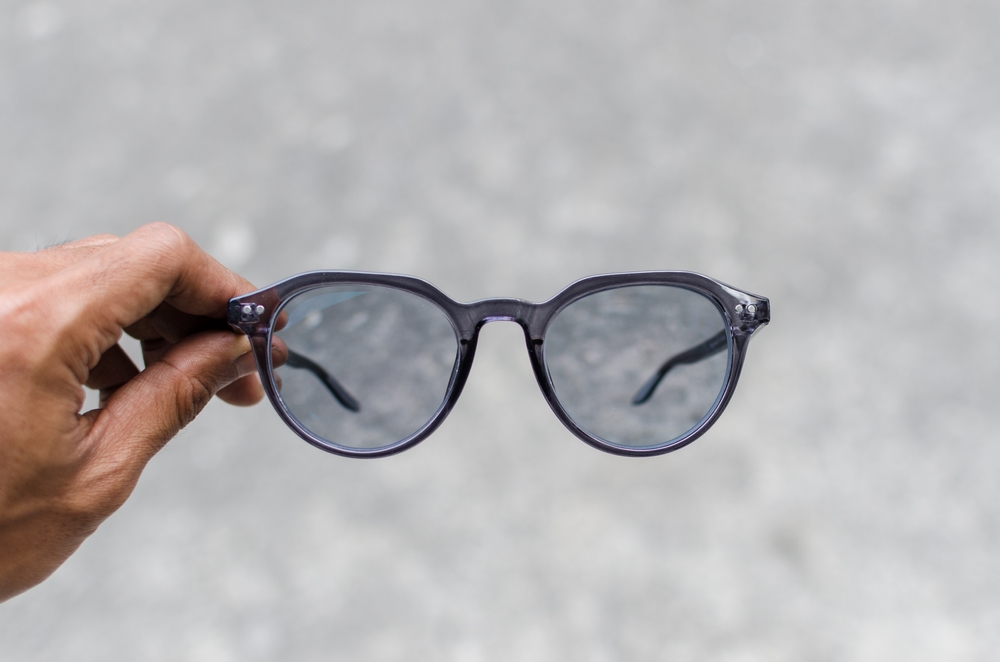 Man's,Hand,Holding,A,Glasses,With,Photochromic,Lenses,On,Grey